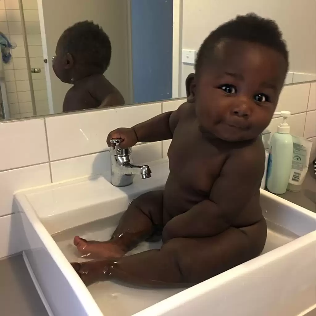 The boy with shiny black skin captivates the viewer’s gaze, defying all beauty standards.